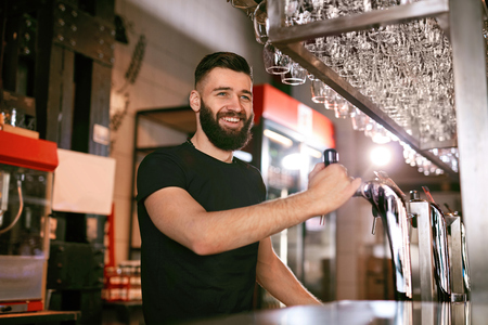 Bar Pub. Male Bartender Standing At Bar Counter Near Beer Taps. High Resolution.の写真素材