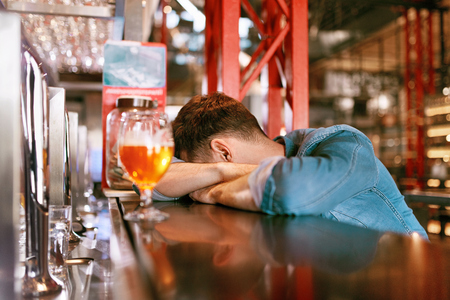 Drunk Man Lying On Bar Counter Near Glass Of Beer In Pub. High Resolution.の写真素材