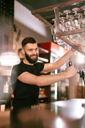 Bar Pub. Male Bartender Standing At Bar Counter Near Beer Taps. High Resolution.の写真素材