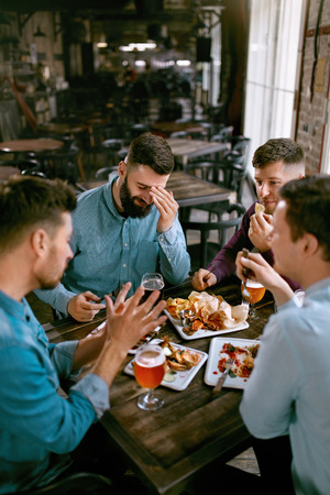 Friends At Dinner Drinking Beer And Eating Food In Pub Restaurant. High Resolution.の写真素材