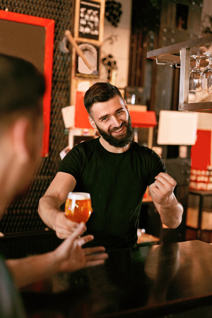 Bartender With Draught Beer In Glass In Bar. Smiling Man Working In Pub. High Resolution.の写真素材