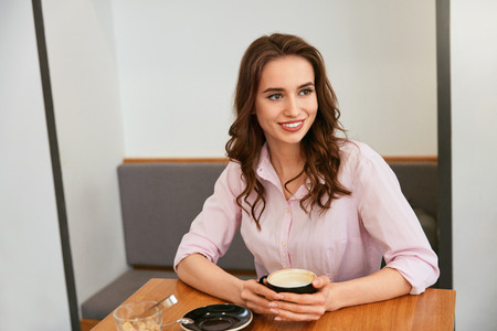 Beautiful Woman In Cafe Drinking Coffee At Table. High Resolution.の写真素材