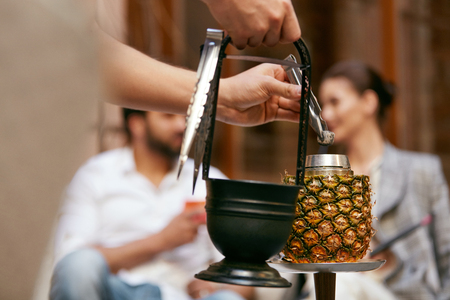 Preparation Pineapple Hookah In Shisha Bar. Man's Hands Preparing Fruit Shisha Cup, Changing Charcoal. High Resolutionの写真素材
