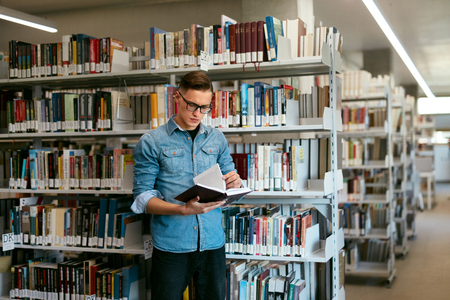 Student Reading Book In College Library. Man Learning Information From Textbook. High Resolutionの写真素材