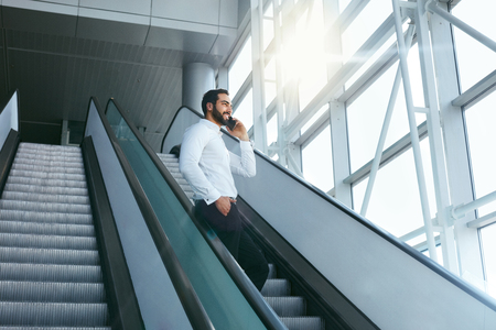 Business Man Talking On Mobile Phone In Office On Stairs. Portrait Of Male Worker Working Using Phone. High Resolutionの写真素材