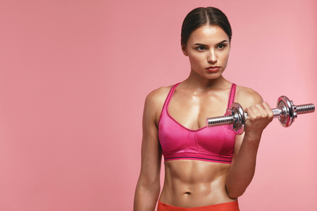 Bodybuilding. Woman Training With Dumbbell On Pink Background, Female Doing Biceps Exercise. High Resolutionの写真素材