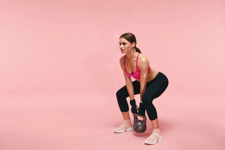 Sport Training. Athletic Woman Doing Squats With Dumbbell On Pink Background. High Resolutionの写真素材