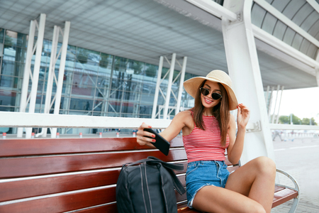 Woman Making Photos On Phone Outdoors, Traveling In Summer. Beautiful Smiling Girl Using Phone On Street. High Resolutionの写真素材