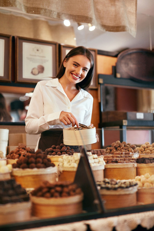 Chocolate Store. Female Seller In Confectionery Shop With Chocolate Sweets. High Resolutionの写真素材