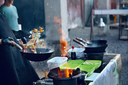 Cooking Food On Fire On Street Festival. Chef Cooking Thai Dish In Wok Outdoors. High Resolution