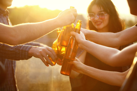 Friends Drinking Beer Outdoors. People Cheering With Beer Bottles. High Resolutionの写真素材
