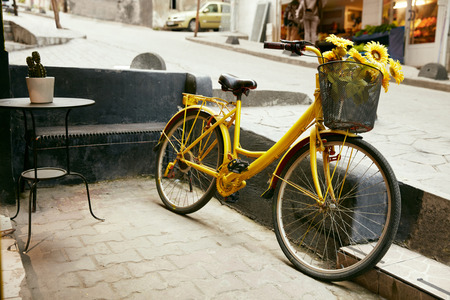 Yellow Bicycle With Basket Of Sunflowers At City Street, Cycle Outdoors. High Resolutionの写真素材
