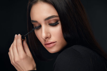 Beauty Makeup. Beautiful Woman With Long Black Eyelashes And Mascara Brush On Black Background. High...