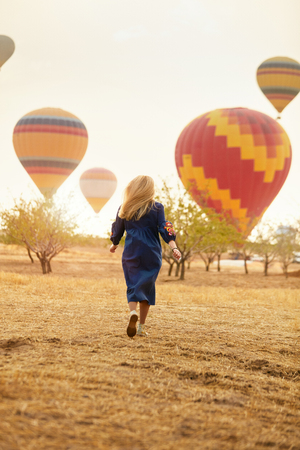 Woman Running In Field With Hot Air Balloons Flying On Background In Nature. High Resolutionの写真素材