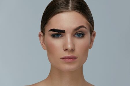 Beauty makeup. Woman coloring eyebrow with gel tint portrait. Girl model setting liquid peel-off brow gel on eyebrowの写真素材
