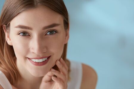 Beauty portrait of smiling woman with white teeth smile. Beautiful happy girl with fresh skin, natural face makeup indoors closeupの写真素材