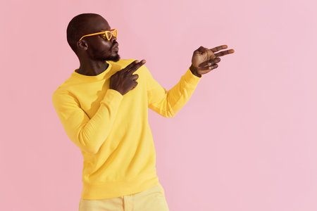 Fashion. Black man in stylish sunglasses and clothes having fun. Colorful portrait of male model in...