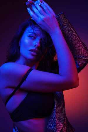 Fashion girl model in color neon lights portrait. Studio shot of beautiful sexy woman dancing in bright vivid pink and purple ultraviolet light at night clubの写真素材