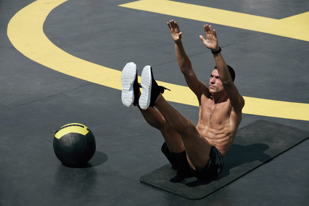 Sport man doing abs exercise, fitness workout outdoors. Fit male athlete practicing abs toe touches...