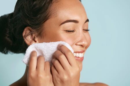 Woman cleaning facial skin with towel after washing face portraitの写真素材