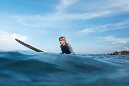 Surfer. Surfing Man On Surfboard Portrait. Guy In Wetsuit Swimming In Ocean. Turquoise Sea And Blue Sky On Background.の写真素材