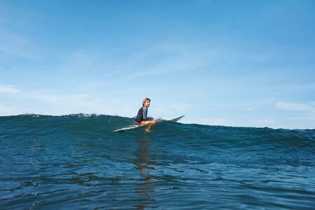 Surfer In Ocean. Surfing Man On Surfboard Catching Wave. Water Sport For Active Lifestyle. Blue Water And Beautiful Sky On Background. の写真素材