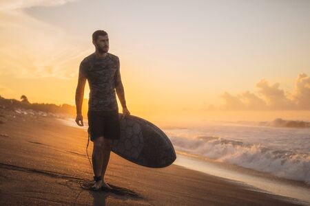 Surfing. Surfer Carrying Surfboard On Ocean Beach. Man Silhouette At Beautiful Sunrise In Bali.の写真素材