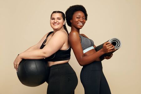 Fitness Friends. Slim And Plus Size Models. Diversity Women In Black Sportswear Holding Fitness Ball And Mat. Sport As Lifestyle.の写真素材
