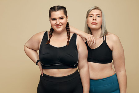 Body Positive. Plus Size Models Portrait. Fat Women In Sportswear On Beige Background. Fitness For...