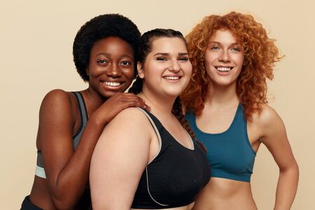 Different Women. Group Of Diversity Models Portrait. Smiling International Female In Fitness Clothes Posing On Beige Background. Body Positive As Lifestyle.の写真素材