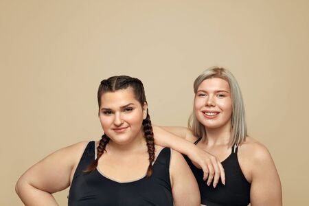 Body Positive. Plus Size Models Portrait. Full-Figured Women In Sportswear On Beige Background. Fitness For Active Lifestyle.の写真素材