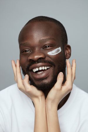 Facial Cream. Skin Care Face Treatment For Man. Beauty Procedure Routine. Female Hand Applies Cosmetology Product On African Model.の写真素材