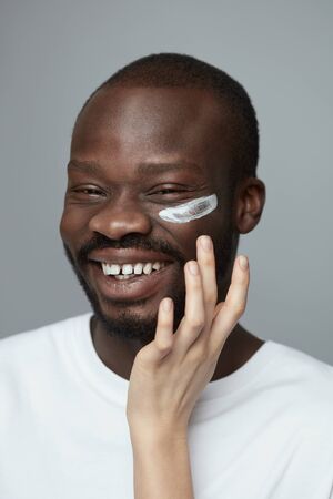 Skin Care. Face Treatment Beauty Procedure For Man. Male Facecare Routine. Female Hand Applies Cosmetology Cream On African Model.の写真素材