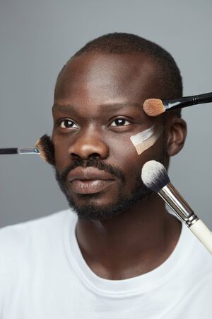 Male Makeup. Facial Beauty Treatment With Cosmetic Products. Female Hands With Brushes Touch Man's Face With Foundation Cream.の写真素材