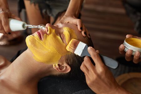 Face Mask. Beautician Applying Yellow Skin Care Product. Spa Beauty Treatment For Relaxed Woman.の写真素材