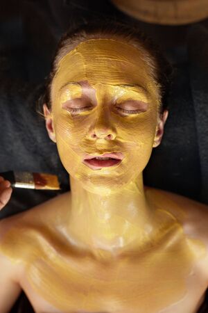 Face Mask. Beautician Applying Yellow Skin Care Product. Spa Beauty Treatment For Relaxed Woman.の写真素材