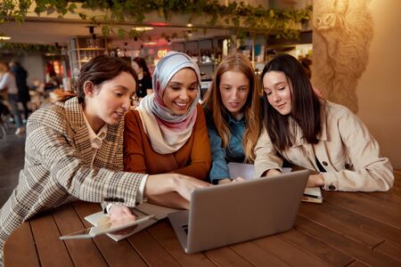 Friends. Women Meeting In Cafe. Four Smiling Girls Sitting In Restaurant With Laptop And Tablet. Diversity Female Working At Bistro. Freelance As Lifestyle.の写真素材