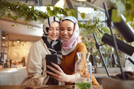 Women. Girls In Hijab Taking Selfie. Friends Meeting In Cafe. Smiling Muslim Female Having Fun In Bistro.の写真素材