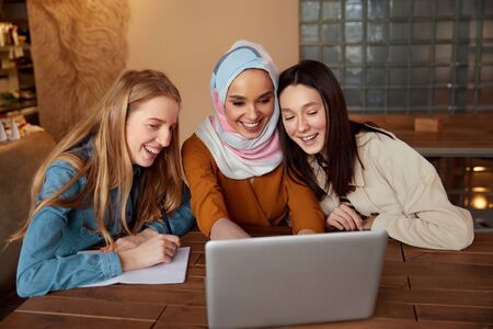 Women. Friends Meeting In Cafe. Group Of Three Young Girls With Laptop Having Fun In Bistro. Diversity Female Working At Restaurant. Freelance As Lifestyle.の写真素材