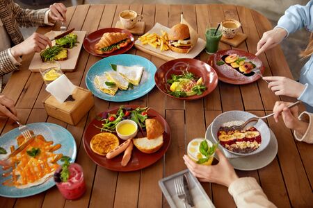 Lunch. Cafe Table With Different Food. Women Having Breakfast In Restaurant. Wooden Surface With Colorful Dishes And Drinks. の写真素材