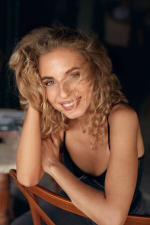 Beautiful Woman. Sexy Blonde Model Relaxing On Wooden Chair. Healthy Natural Look In Beauty Portrait. Female Curly Hairstyle And Nude Makeup.の写真素材
