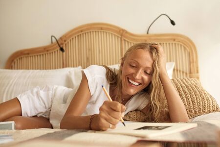 Work From Home. Mature Woman Uses Notepad Sitting On Bed. Beauty Portrait Of Middle Age Female Studying And Working. Comfortable Workplace Concept.の写真素材