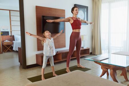 Family Workout At Home. Mother And Daughter Exercising In Living Room. Little Girl And Young Woman Practicing On Mat. Sport Routine For Active Lifestyle.の写真素材