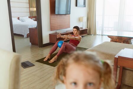 Home Workout. Social Isolation For Staying Active And Fit. Mother Doing Exercise, Daughter Taking Selfie On Smartphone. Young Woman Practicing In Living Room During Quarantine.の写真素材