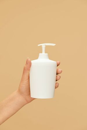 Hygiene. Liquid Soap Bottle In Caucasian Female Hand On Beige Background. Daily Personal Hygiene Routine And Skin Care For Coronavirus Prevention. Wash Your Hands For Staying Healthy.の写真素材