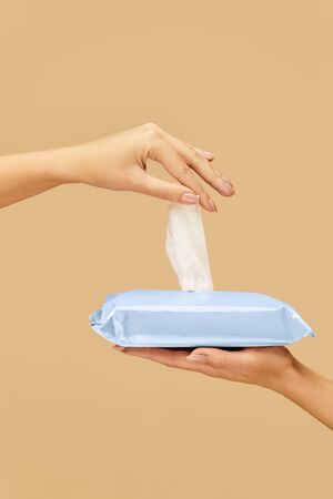 Wipes. Female Hand Picked Wet Napkin From Blue Pack On Beige Background. Home And Travel Hygiene For Coronavirus And Bacterial Infection Prevention.の写真素材