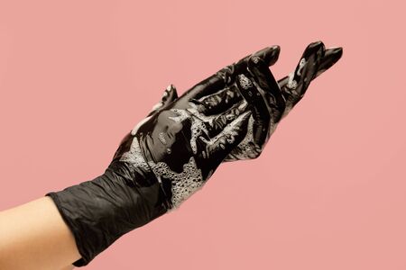 Personal Hygiene. Hands In Black Gloves Covered With Soap Foam Against Pink Background. Using Antibacterial Products And Washing Hands For Coronavirus Infection Prevention.の写真素材