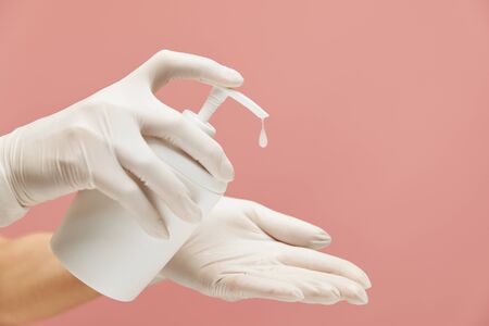 Personal Hygiene. Hands In White Gloves With Bottle Of Soap On Pink Background. Daily Routine With Antibacterial Products For Coronavirus Prevention And Staying Healthy.の写真素材