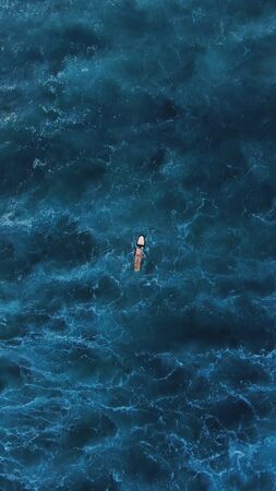 Top View. Surf Man On White Surfboard Swimming On Ocean Background. Active Lifestyle At Beautiful Blue Sea.の写真素材
