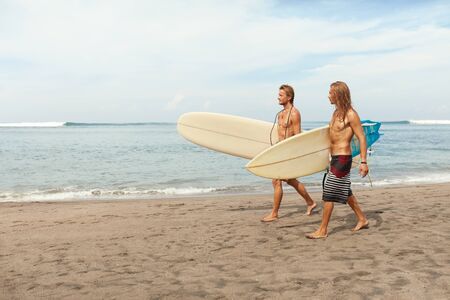 Surfing. Handsome Surfers With Surfboards. Young Men Walking On Sandy Beach. Active Lifestyle, Water Sport On Beautiful Ocean Background.の写真素材